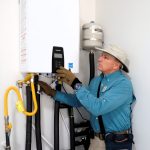 Inspector adjusting tankless water heater controls during new home inspection in Johns Creek