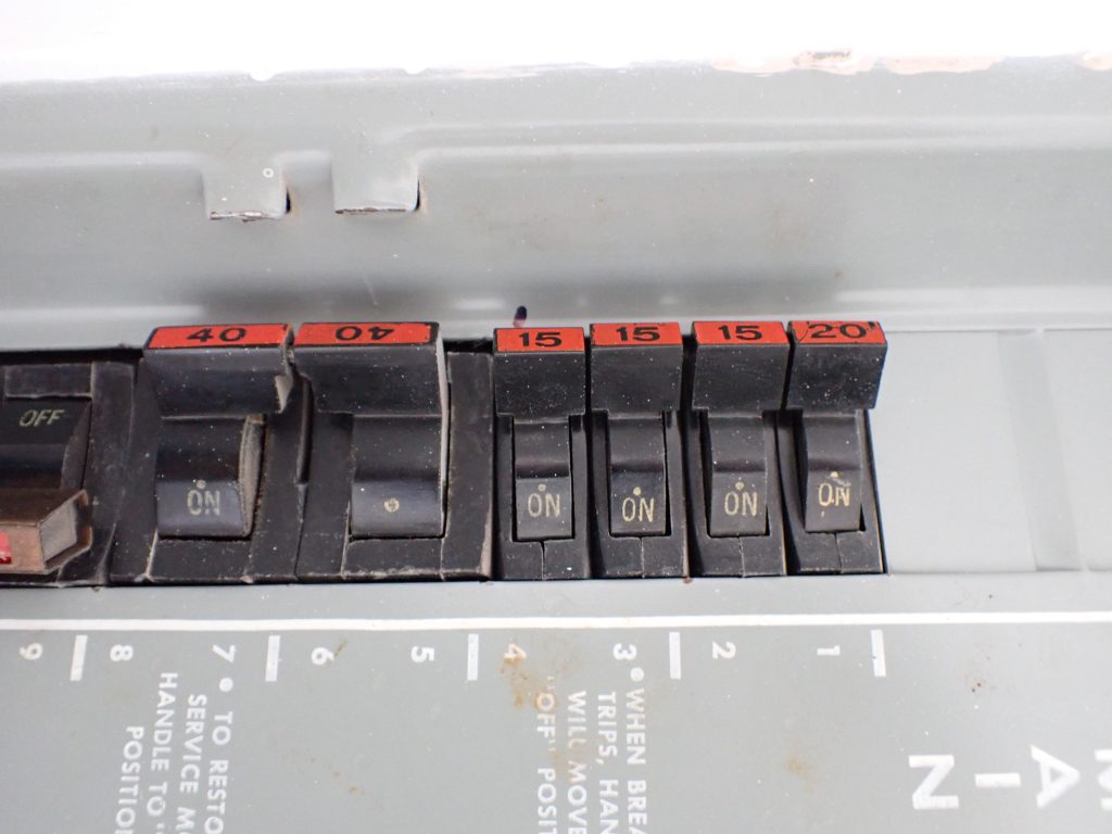 Stab-Lok breaker arrangement with red breaker markings in an older electrical panel. Caption: Red breaker markings and the overall breaker layout are common visual indicators of a Stab-Lok panel.